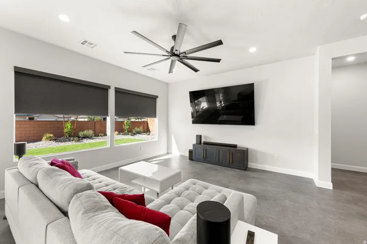 Recessed lighting, ceiling fan, expansive windows with roller shades, and a built-in media console