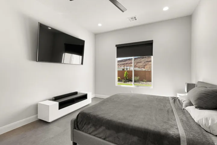 Recessed lighting, ceiling fan, expansive window with roller shade, and wood-finish flooring