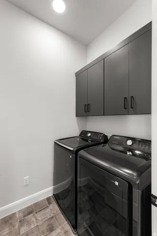Recessed ceiling lighting, built-in dark cabinetry, and tile flooring