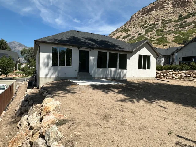 Stucco exterior with multiple windows, leading to a concrete patio