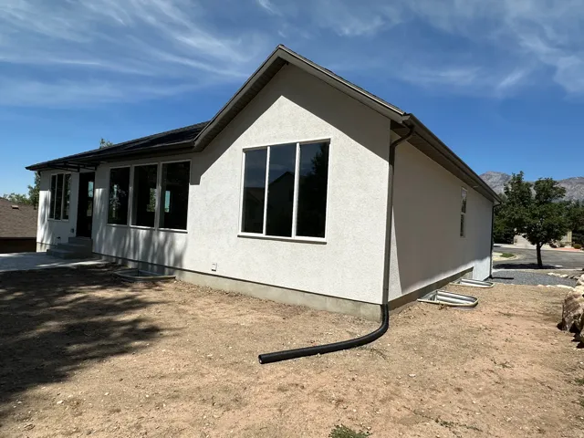Stucco exterior with multiple large windows, covered entryway, and a concrete patio