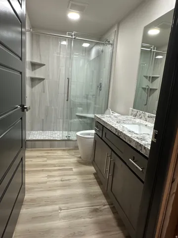 Glass-enclosed shower with a built-in bench and recessed shelving