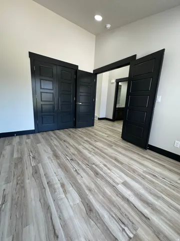 Wood-finish flooring throughout, modern black interior doors, recessed lighting, and high ceilings