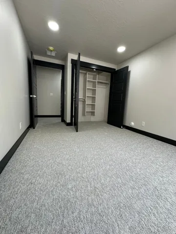 Recessed lighting illuminates the grey patterned carpeting and light-colored walls