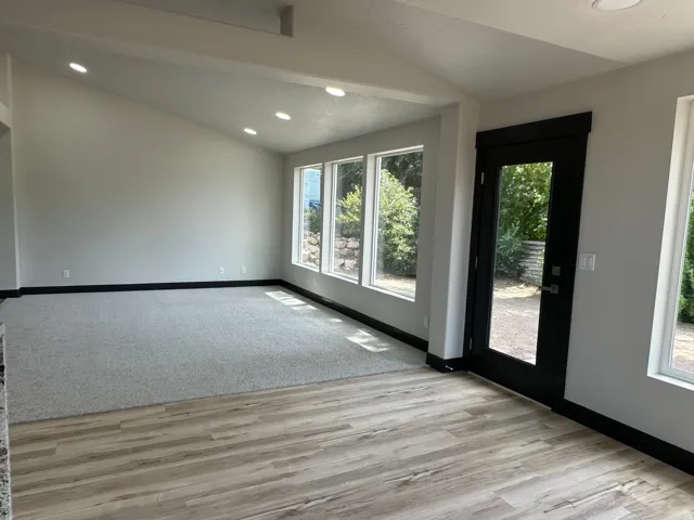 Vaulted ceilings with recessed lighting, expansive windows, wood-finish flooring, and a full-light exterior door