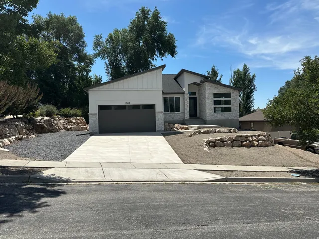 Modern exterior with stone accents, a dark garage door, and a concrete driveway