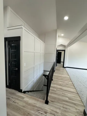 Wood-finish flooring, recessed lighting, and a contemporary black metal stair railing