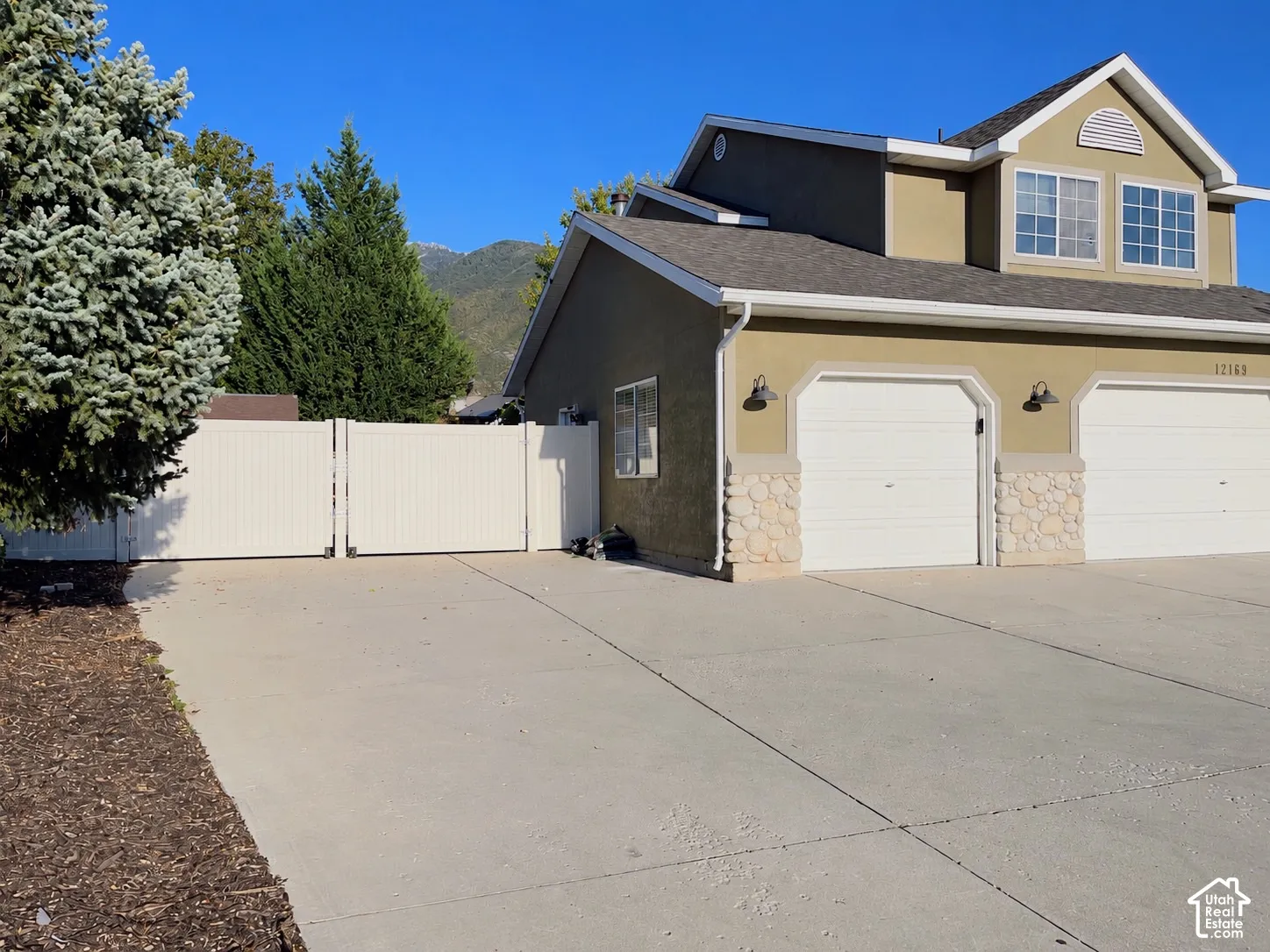 Two-car garage with stone veneer accents, stucco exterior, and multi-pane windows
