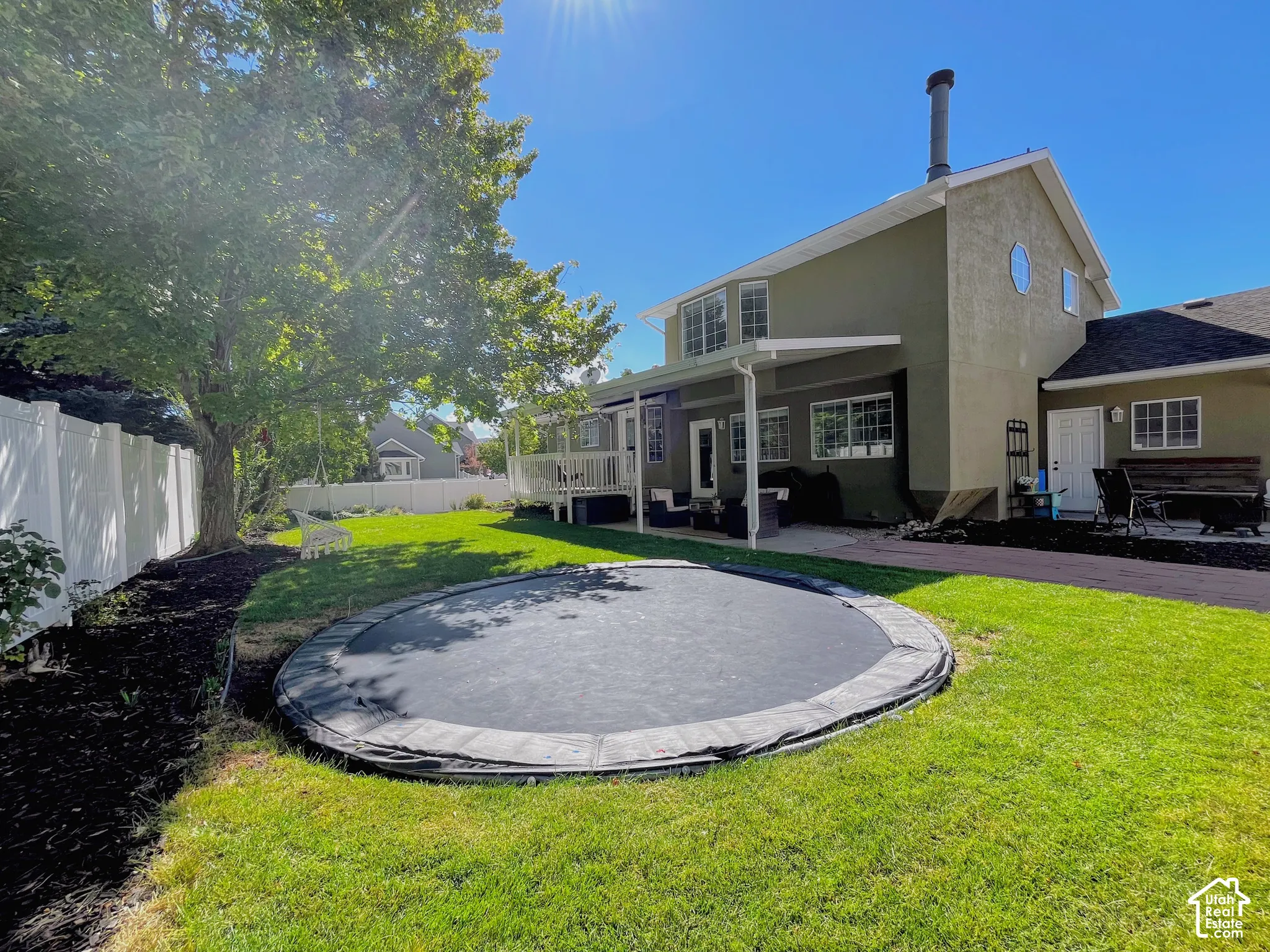 Rear exterior with stucco finish and multiple windows, featuring an outdoor patio with a partial awning and a ground-level deck