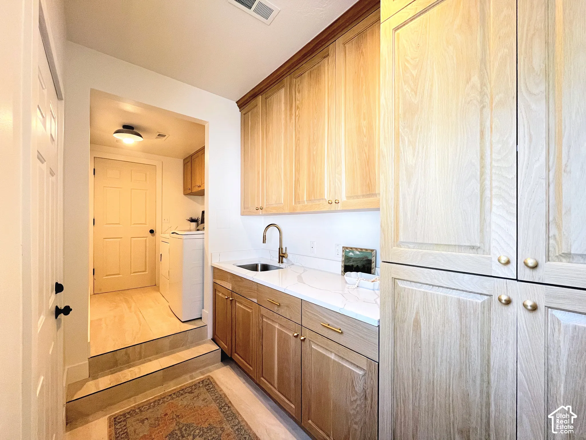 Light wood-finish cabinetry, white countertop, and integrated sink with a gooseneck faucet