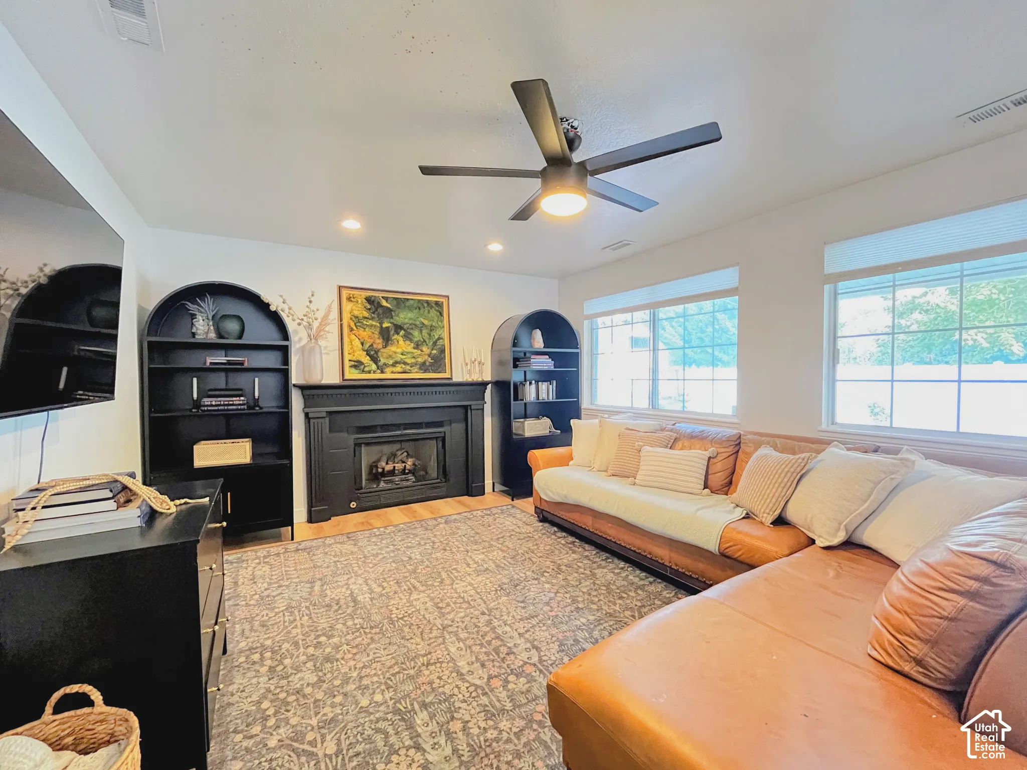 Fireplace with dark mantel, wood-finish flooring, recessed lighting, and a ceiling fan