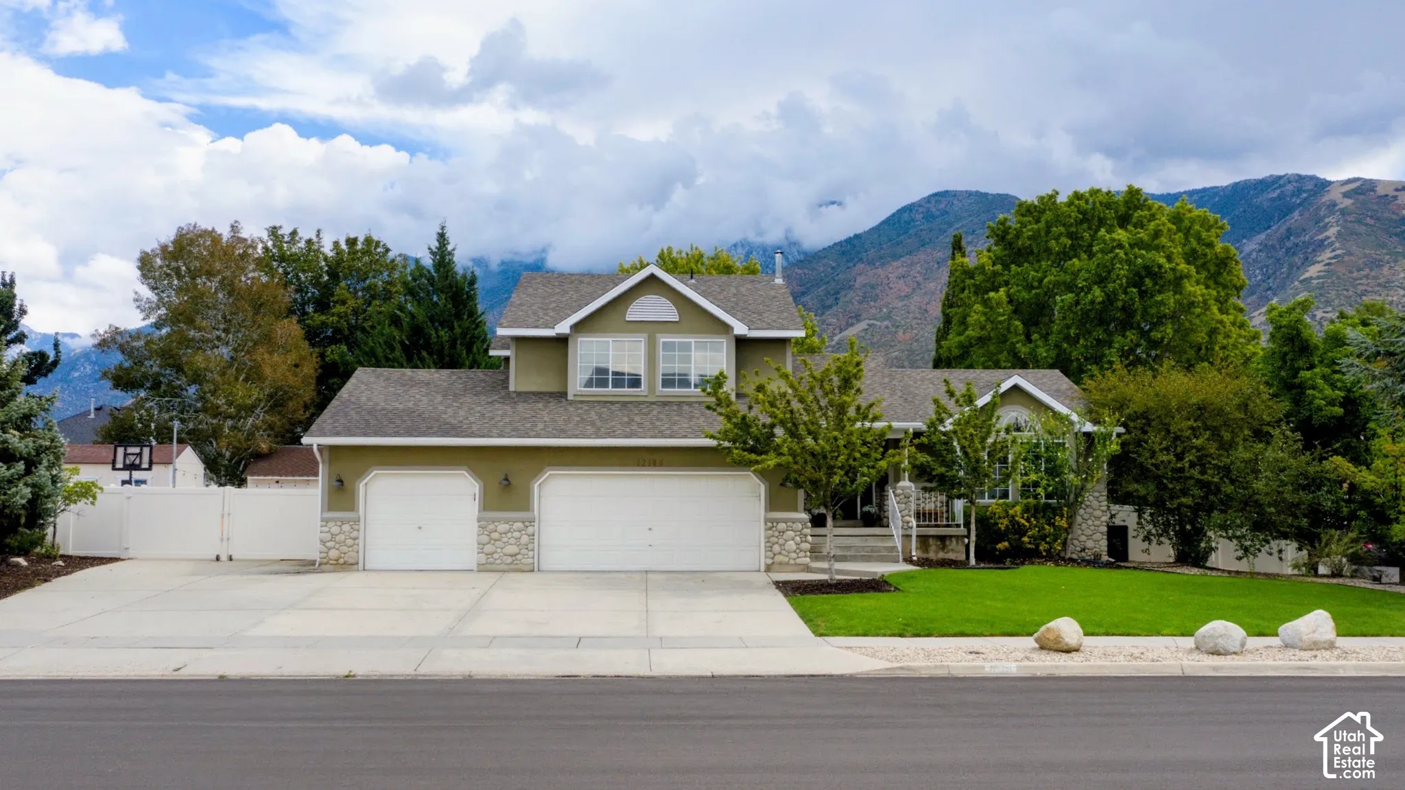 Two-story residence featuring a two-car garage, stone accents on the facade, and a well-maintained lawn