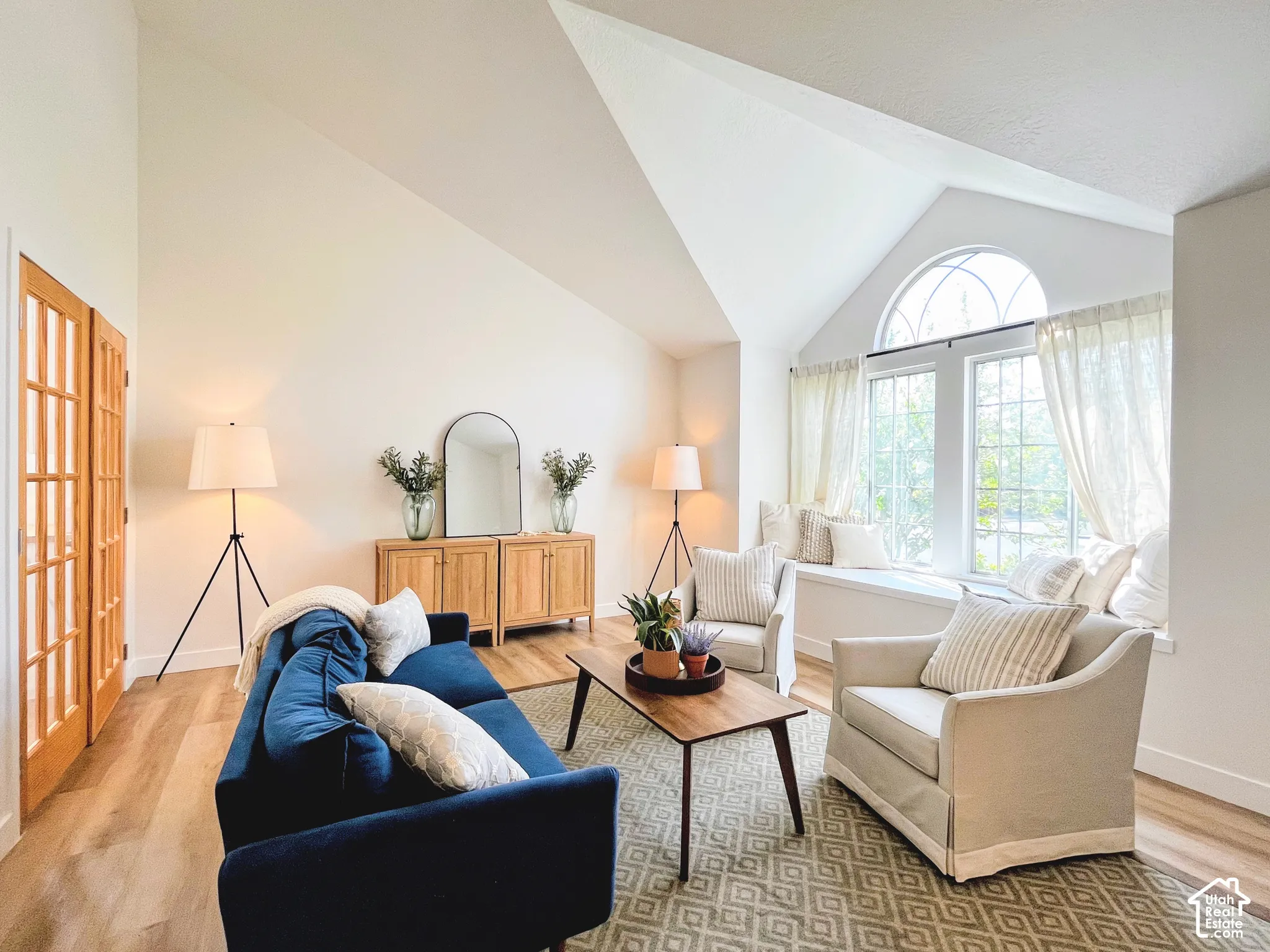 Vaulted ceilings, wood-finish flooring, French doors, a built-in window seat, and an arched transom window