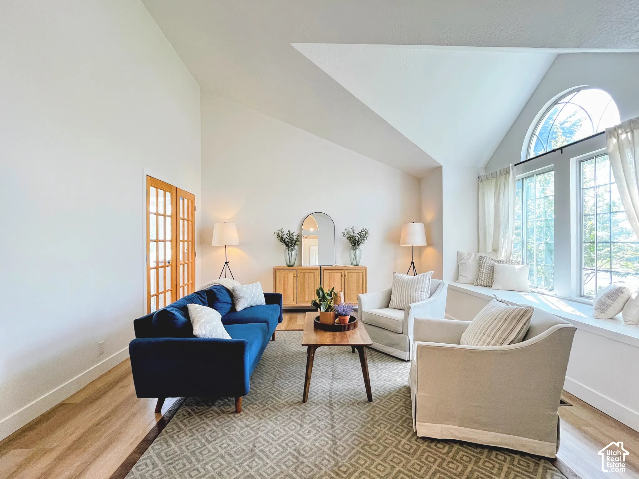 Vaulted ceilings, wood-finish flooring, arched window, built-in window seating, and interior French doors
