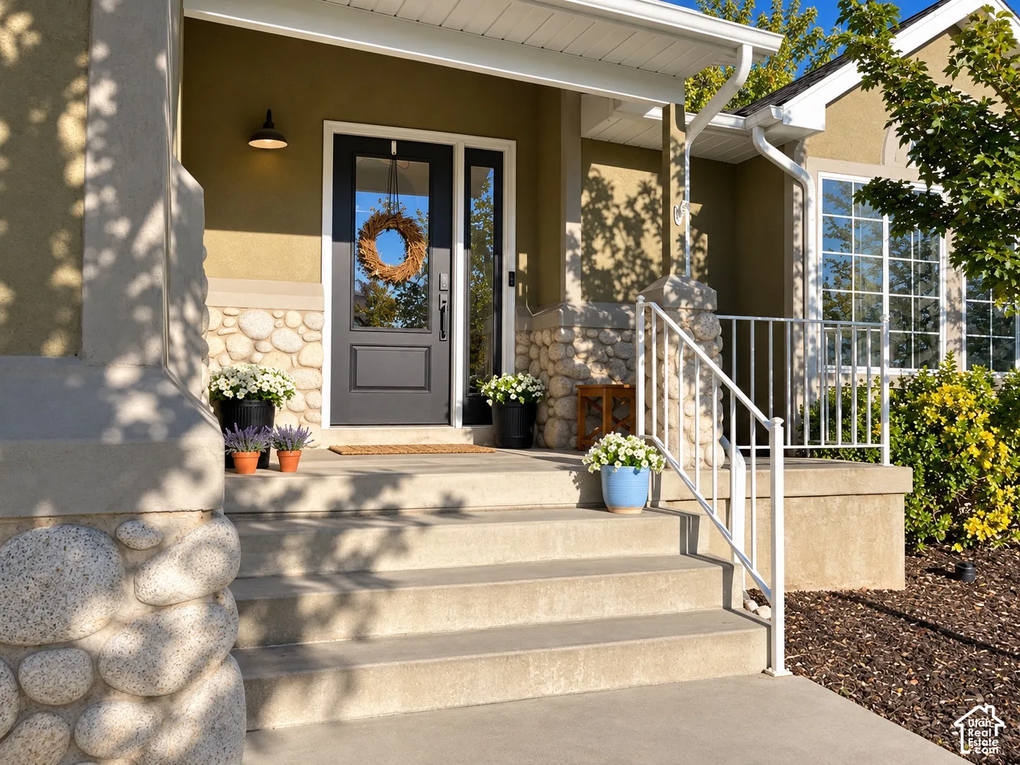 Welcoming entry featuring a dark-paneled door, sidelight window, stone fa