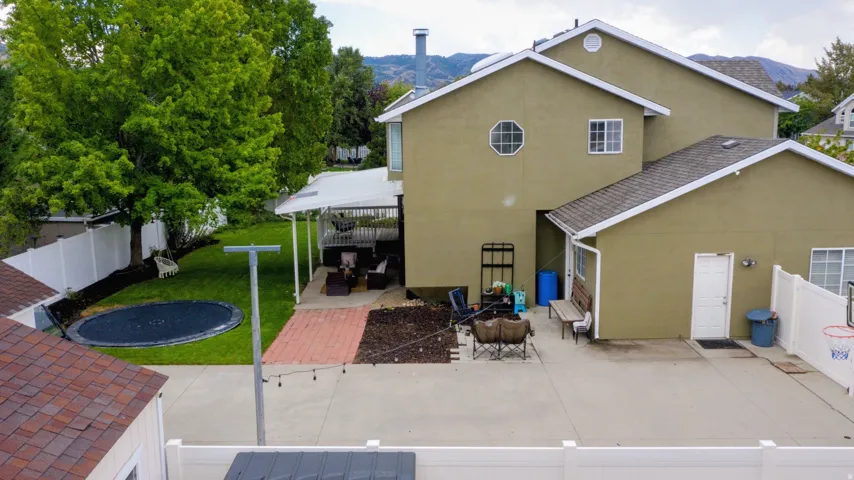 Two-story exterior with stucco finish, a covered patio, a manicured lawn, and a paved patio area