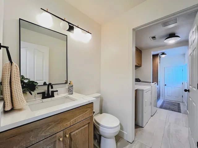 Vanity with wood-finish cabinetry, quartz countertop, and black fixtures