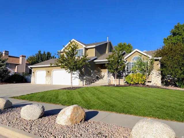 Two-story residence featuring a stucco and stone veneer exterior, an arched entry window, and a two-car garage