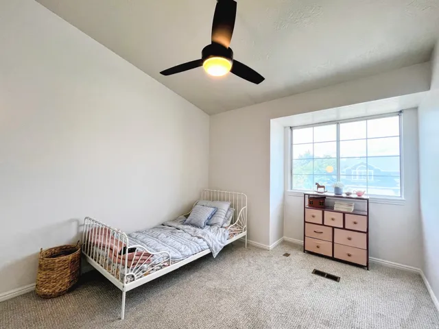 Carpeted room with a ceiling fan, white walls, and a large window