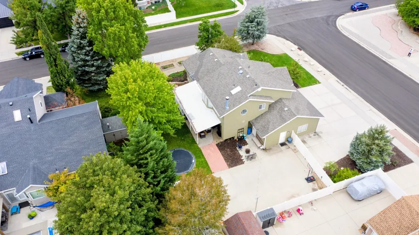 Two-story residence with a light green exterior siding, gray shingle roofing, and multiple mature trees