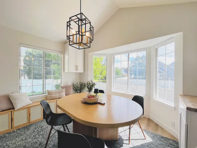 Vaulted ceiling with a geometric pendant light fixture, bay windows, wood-finish flooring, and built-in cabinetry