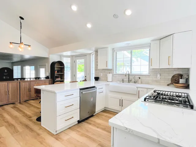 Kitchen featuring white cabinetry, quartz countertops, a farmhouse sink, subway tile backsplash, and wood-finish flooring