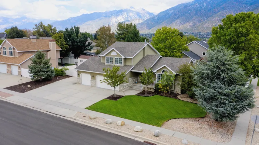 Two-story residence featuring a two-car garage, mature landscaping, and an expansive front lawn
