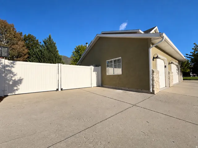 Two-car garage with carriage-style doors, stone column accents, exterior wall sconces, and a stucco finish