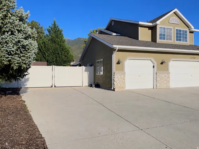 Two-car garage with stone veneer accents, stucco exterior, and multi-pane windows