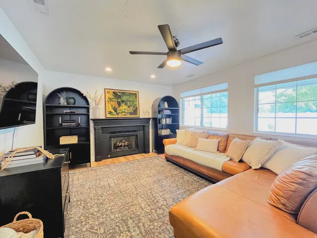 Fireplace with dark mantel, wood-finish flooring, recessed lighting, and a ceiling fan
