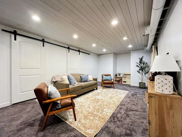 Recessed lighting, wood-finish plank ceiling, barn doors with black hardware, and carpeted flooring