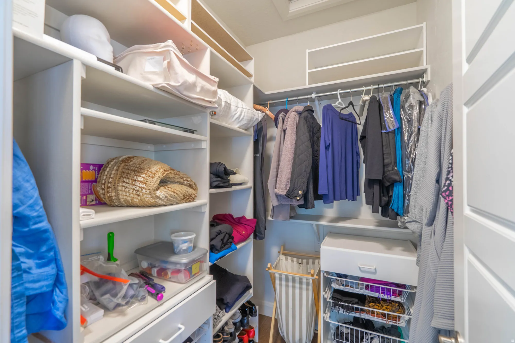 Built-in white shelving, integrated hanging rods, and an overhead shelf system