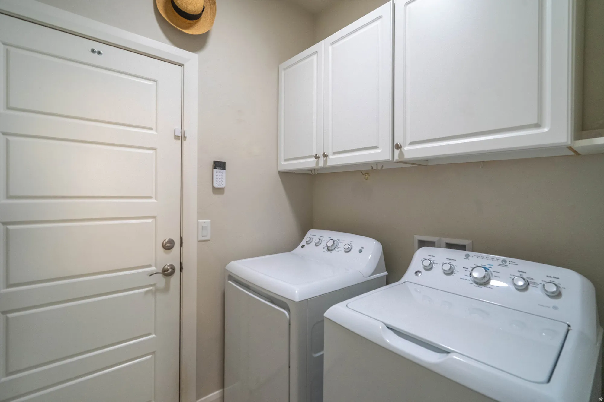White paneled door, wall-mounted white cabinetry, and light-toned walls