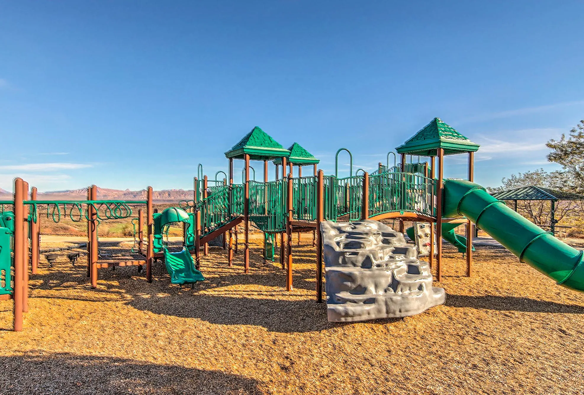 Playground featuring multiple slides, climbing structures, monkey bars, and soft ground covering