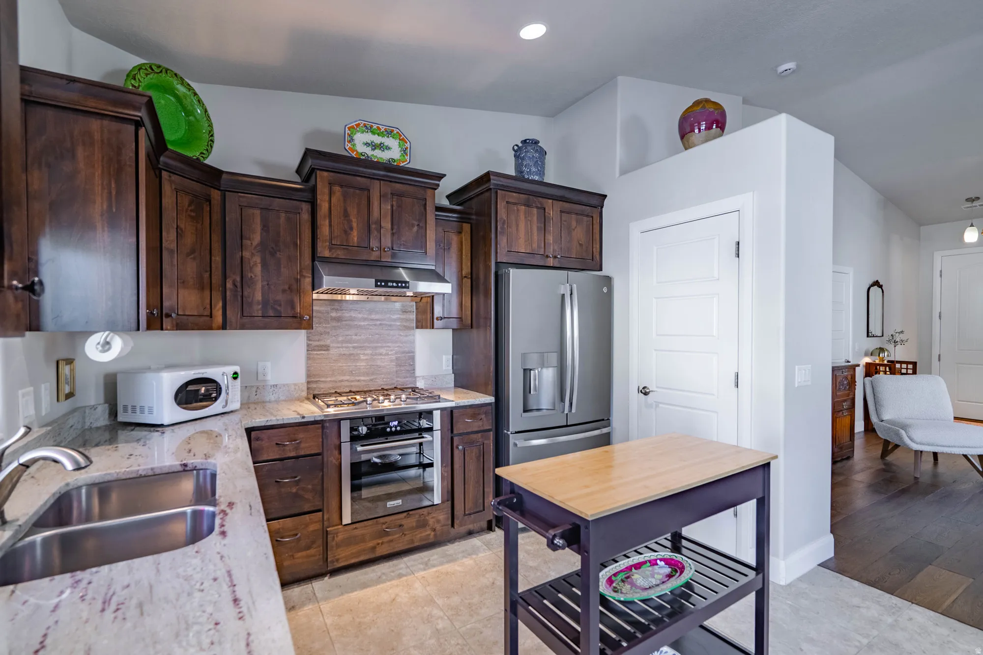 Kitchen featuring granite countertops, wood cabinetry, stainless steel appliances, a tile backsplash, and tile flooring