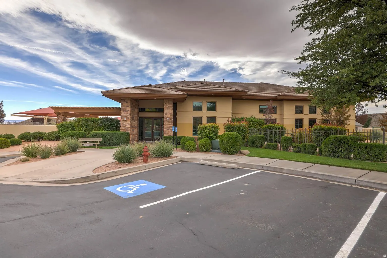 Stucco exterior with stone accents, covered entrance, paved parking, and established landscaping
