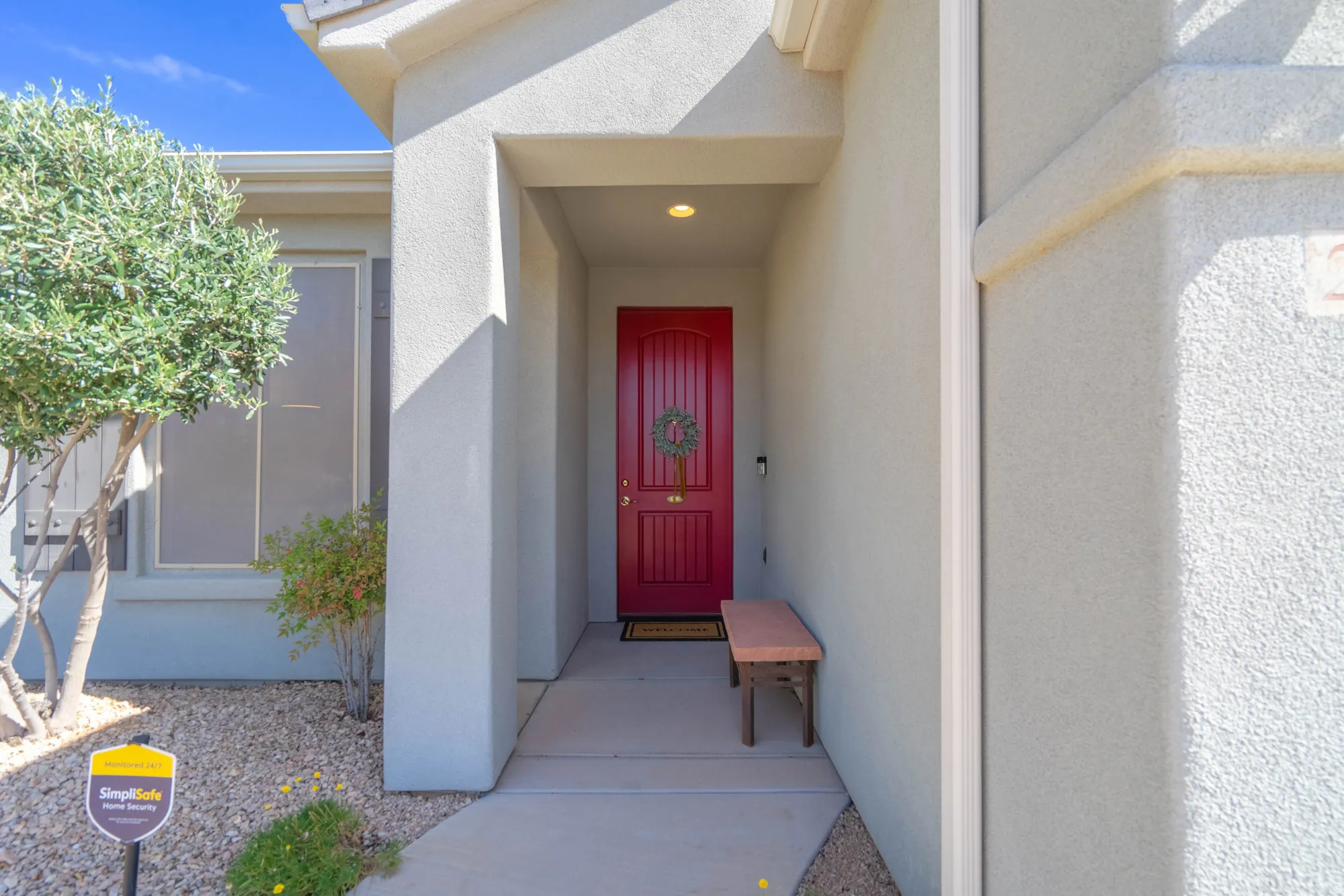 Recessed entry with a paneled red door, stucco exterior, and accent trim