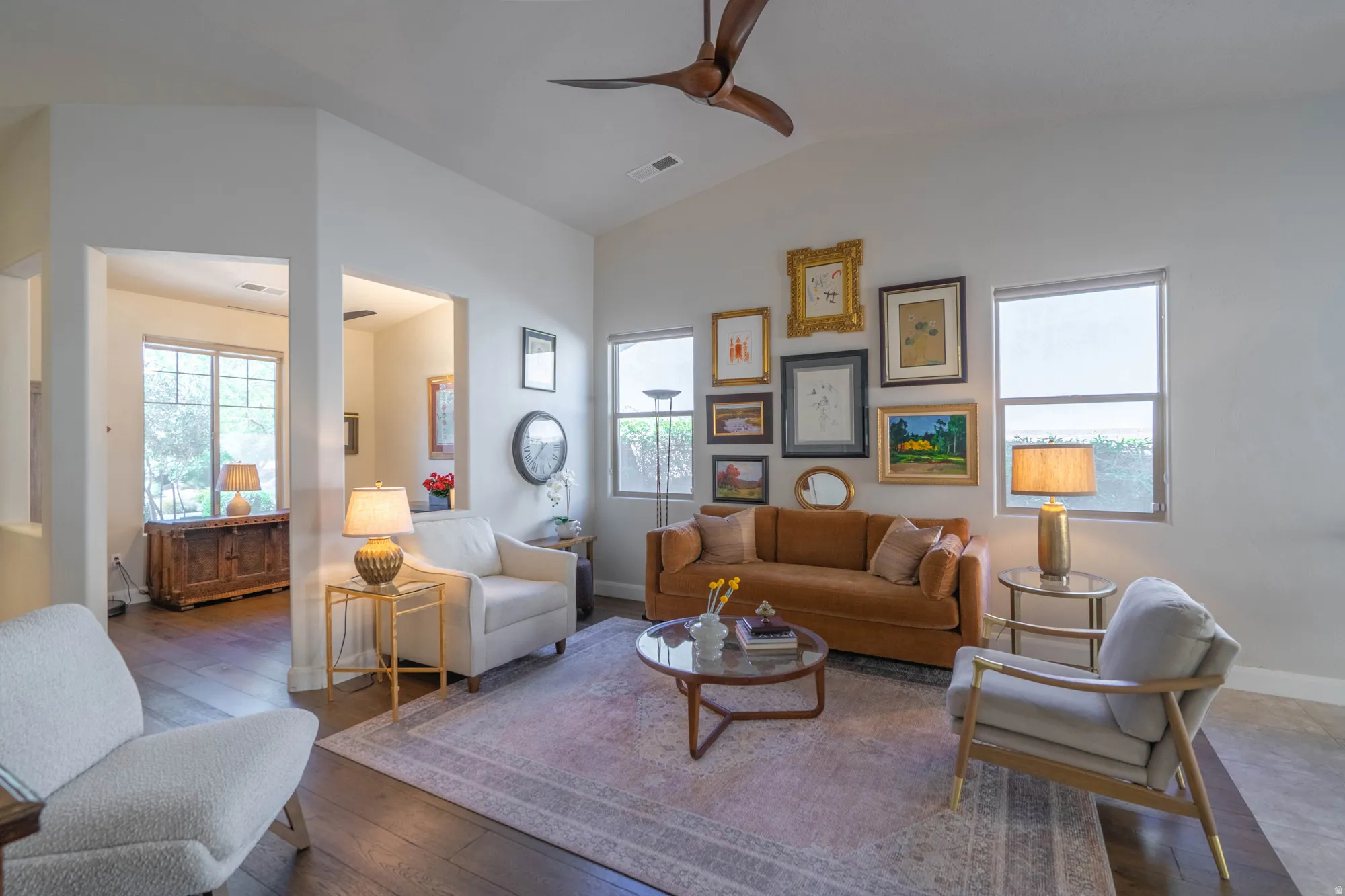 Vaulted ceiling with a contemporary ceiling fan, dark wood-finish flooring, and multiple windows providing natural light