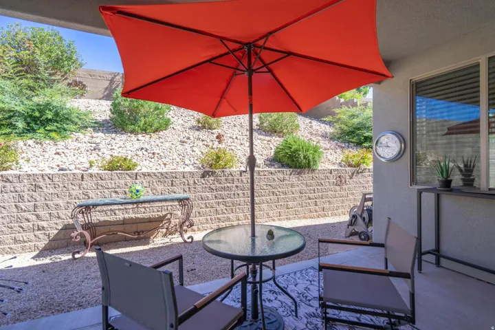 Paved patio with an overhead cover, a stone retaining wall, and a xeriscaped hillside