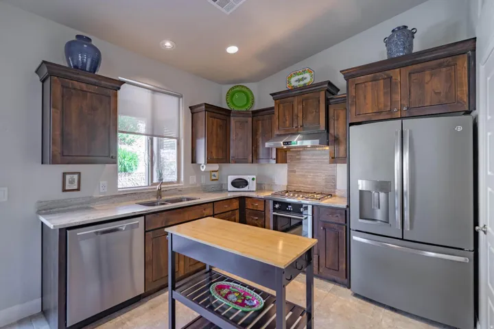 Kitchen featuring wood cabinetry, stainless steel appliances, a double basin sink, and light-toned countertops