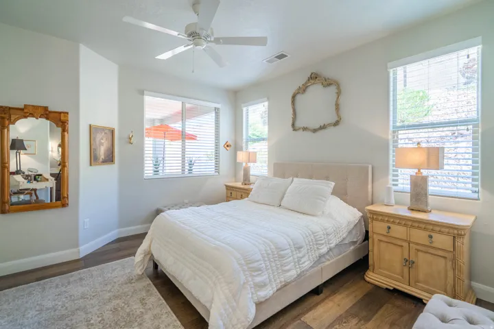 Wood-finish flooring, ceiling fan, multiple windows with blinds, and light-colored walls