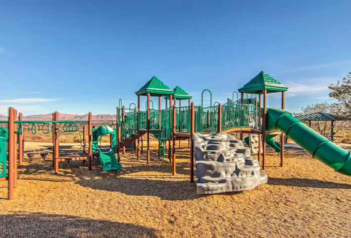 Playground featuring multiple slides, climbing structures, monkey bars, and soft ground covering