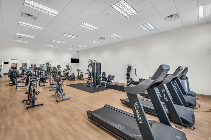 Fitness center with wood-finish flooring, drop ceiling with integrated lighting, and multiple exercise machines