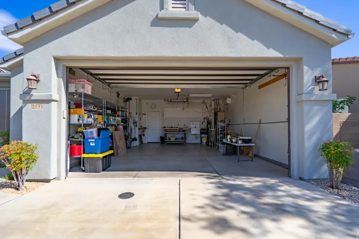 Two-car garage with concrete driveway and exterior wall sconces