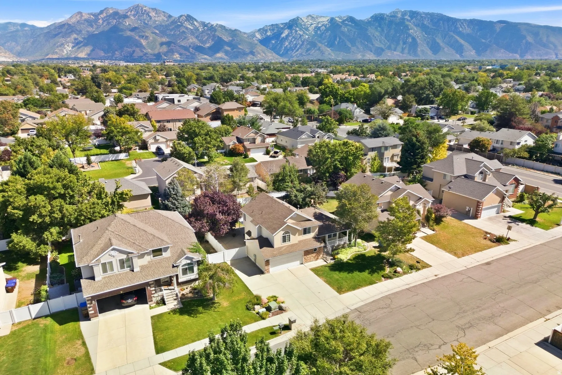 Residential neighborhood with mature trees, established landscaping, and mountain backdrop