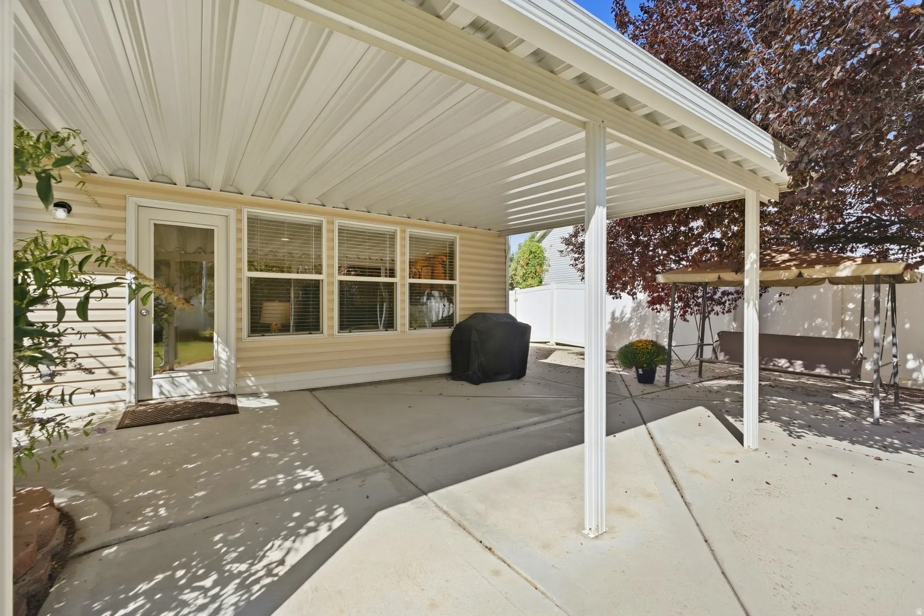 Covered patio with concrete flooring, multiple windows, and exterior siding