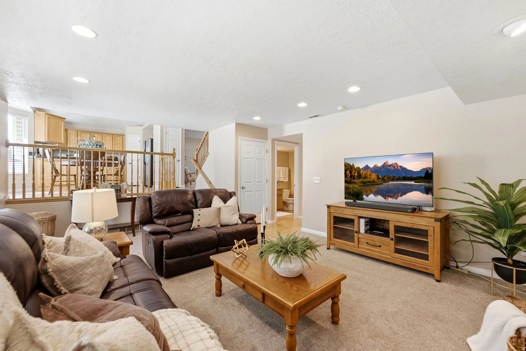 Recessed ceiling lighting, carpeting, and a half-wall with wood spindle railing
