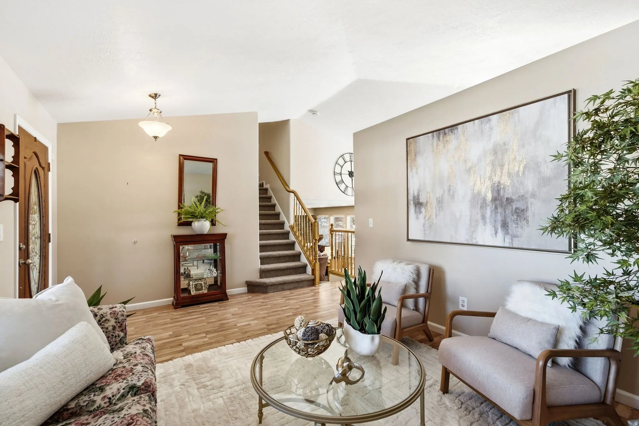 Vaulted ceiling with a central pendant light fixture and wood-finish flooring