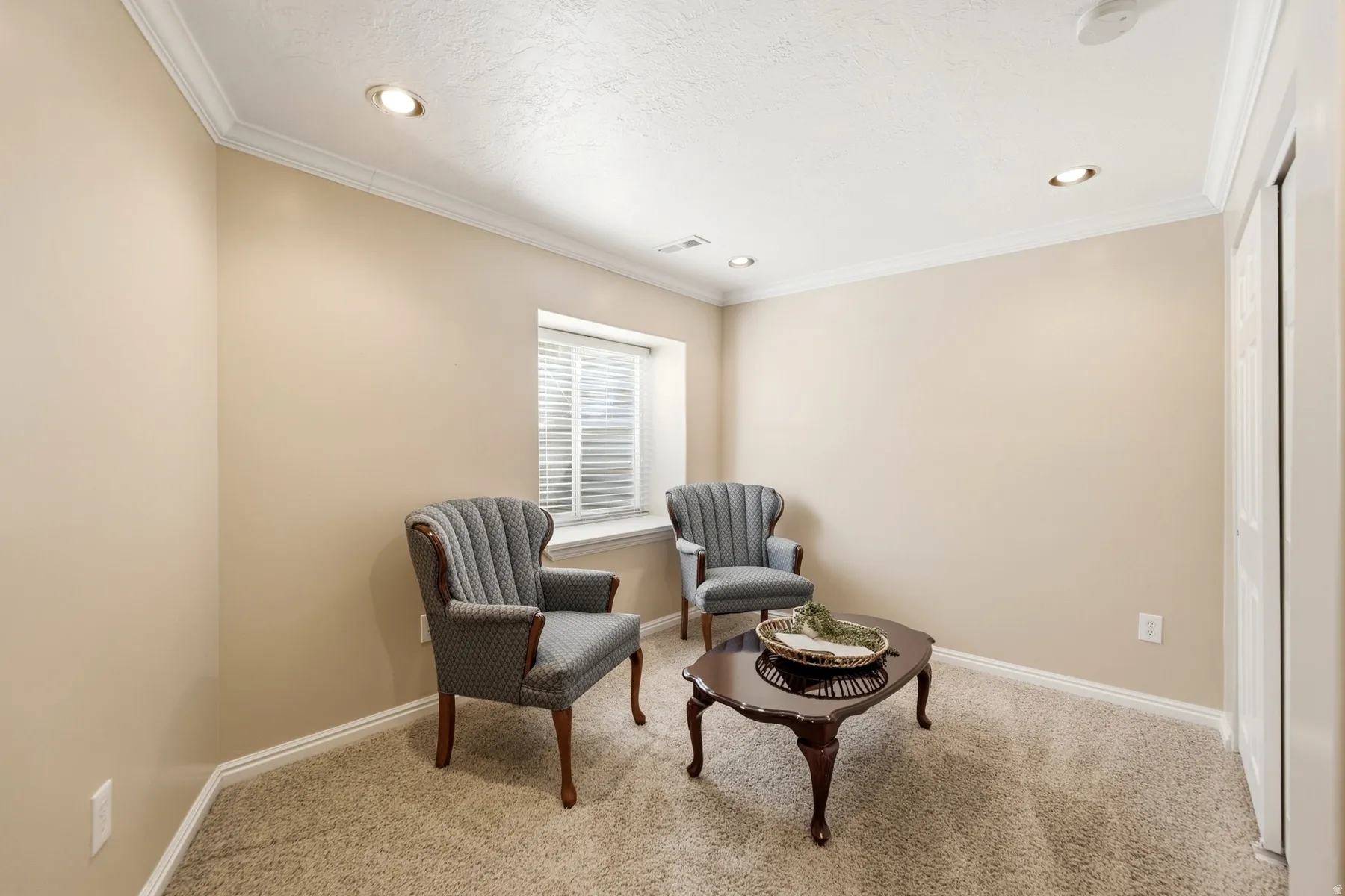 Recessed lighting, crown molding, a window with blinds, and neutral carpet