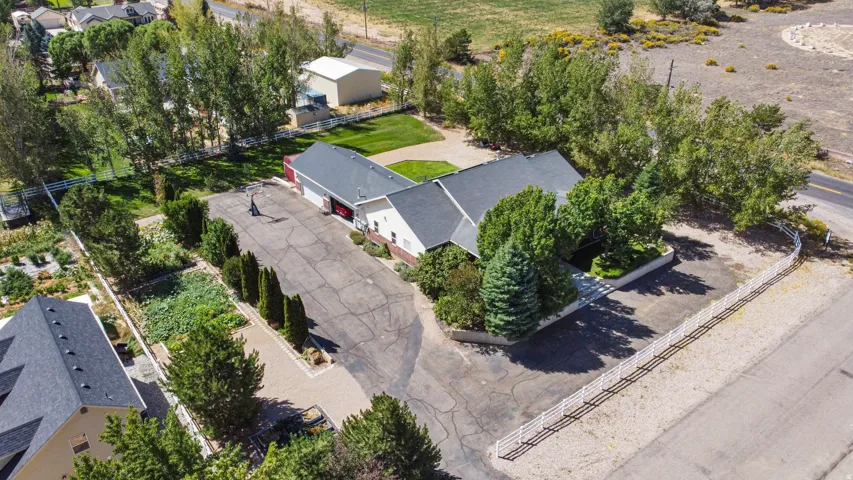 Expansive property featuring a multi-gable roofline, attached garage, paved driveway, and mature landscaping